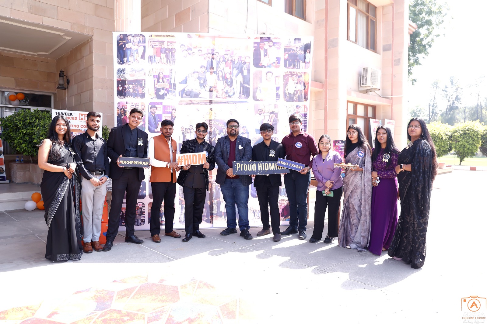 HiDM team and alumni celebrating together with props at the 6th-anniversary event.